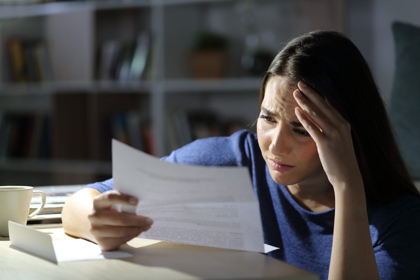 worried girl reads bad news on letter at night at home